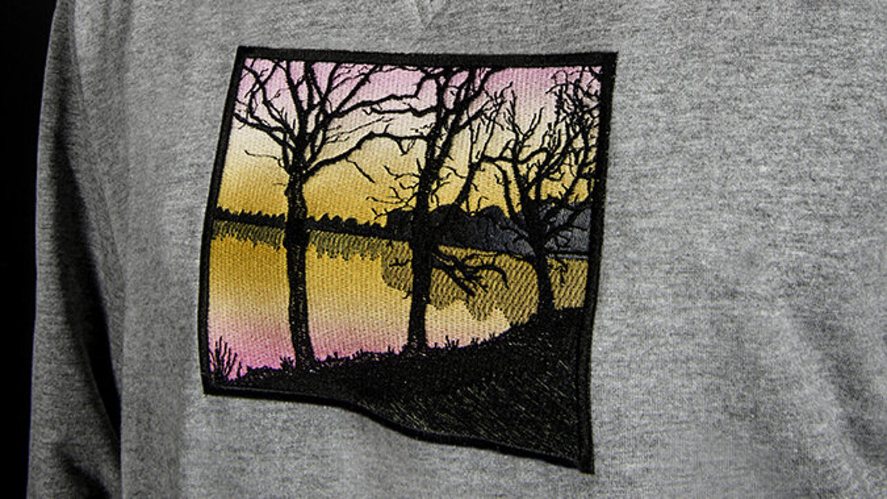 Sunset embroidery design made with Madeira Coloreel thread on a grey shirt